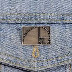 Detailed close-up of golden ratio Fibonacci spiral metal brooch on blue denim jacket pocket