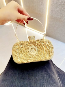 Detail of evening clutch featuring golden floral rhinestone patterns and round handle