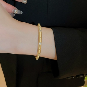 Detail of gold-plated brushed texture cuff bracelet with inlaid cubic zirconia stones