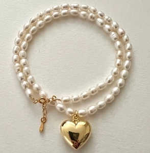 Detail of double-layer white pearl necklace with a polished gold heart pendant