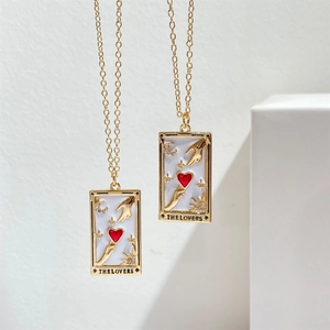 Detail of gold tarot necklaces with The Lovers pendant featuring pink enamel and stars