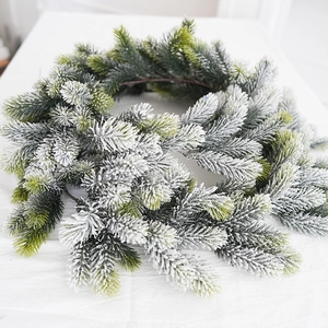 Green flocked Christmas garland with white faux snow on minimalist fabric background