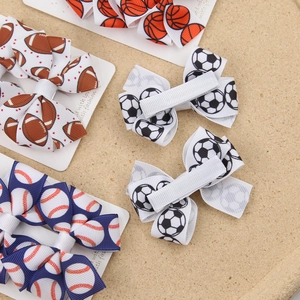 Close-up of sports theme bow clips showing football print detail and metal duckbill clip