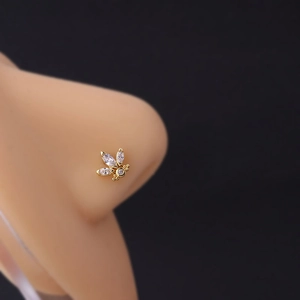 Close-up of a gold butterfly nose stud with white zircon crystals on a female model