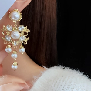 Close-up of vintage gold flower earrings with white pearls and sparkling crystals on model
