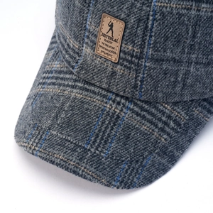 Macro view of plaid tweed texture and brown leather patch on a winter baseball cap