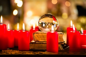 Macro shot of a clear crystal ball suncatcher on vintage books with warm candle light
