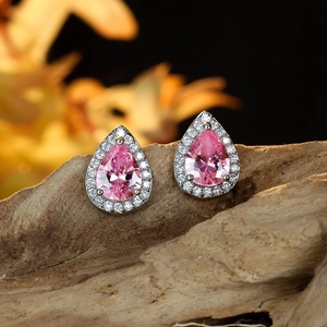 Pink pear-cut zircon stud earrings with silver plating on a rustic wood background