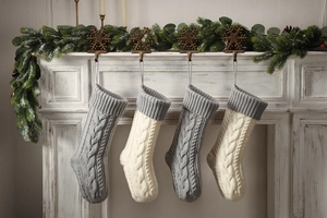 Close-up of knitted Christmas stockings in grey and ivory on a vintage white fireplace