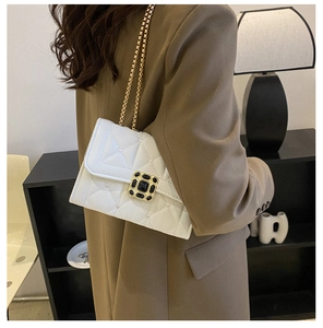 Detail of white quilted chain bag with gold buckle on model in stylish office setting