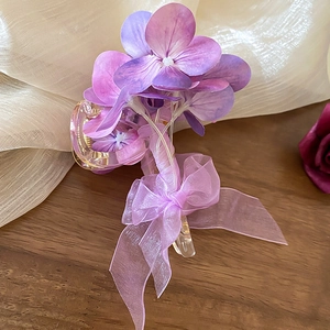 Detail von lila Organza-Schleife und Hortensienblüten auf transparentem Haargreifer