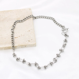 Minimalist silver Cuban chain necklace with knot design and OT buckle on white fabric