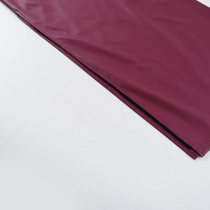 Détail d'une robe en cuir PU bordeaux montrant les coutures fines et la fente latérale