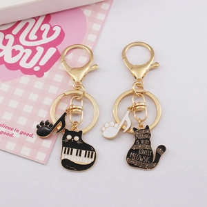 Golden alloy cat keychain set featuring piano keys and musical note pendants