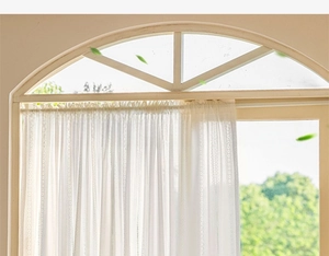 Close-up of white lace curtain with vertical hollow embroidery and scalloped edges