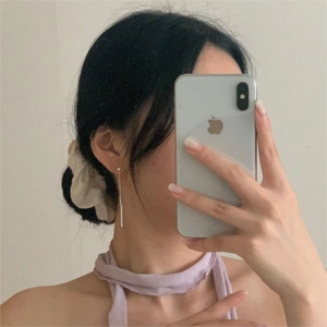 Detail of 925 sterling silver long tassel earrings and beige scrunchie on a model
