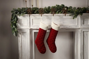 Macro detail of red fish-scale knit Christmas stockings hanging on a vintage white mantel