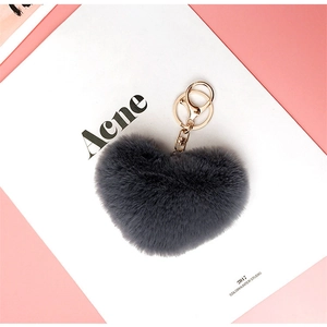 Close-up of fluffy dark grey plush heart keychain with gold alloy lobster clasp on pink background
