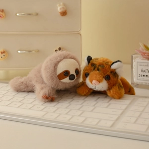 Simpatici animali magnetici in peluche con bradipo e tigre su una tastiera bianca