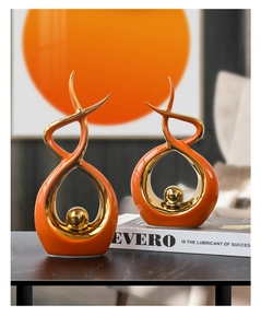 Close-up of modern orange and gold abstract ceramic sculptures on a black marble surface