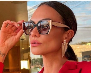 Detail view of cat-eye sunglasses with black and white frames and golden fringe earrings