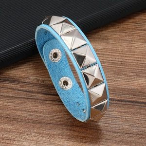 Macro shot of blue leather bracelet featuring silver square pyramid studs and snap closure