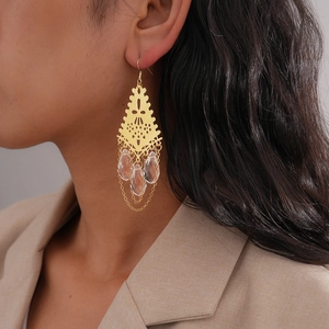 Détail de boucles d'oreilles dorées vintage avec gouttes d'eau sur un modèle