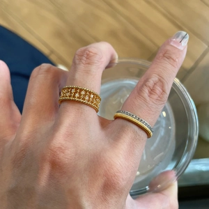 Close-up of vintage style gold brushed kitten emerald rings on a hand holding a cup