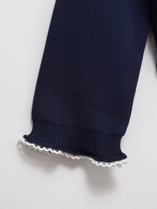 Close-up of navy knit cardigan ribbed cuff with white scalloped edge trim detail