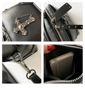 Detail of silver cross pendant and metal rivets on punk style black PU leather bag