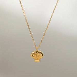 Macro detail of a gold shell pendant showing detailed textures and polished finish