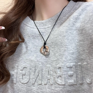 Close-up of a silver liquid metal mobius pendant necklace worn with casual grey hoodie