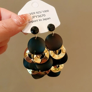 Macro detail of geometric black and gold dangle earrings with S925 silver studs