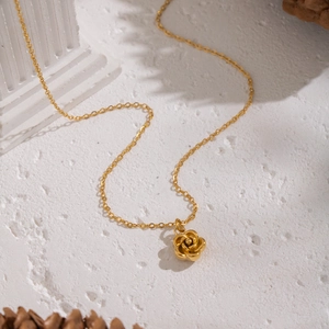 Exquisite gold camellia flower pendant necklace on a minimalist stone display stand