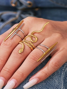 Dettaglio di un anello a serpente dorato e fasce geometriche sulla mano di un modello