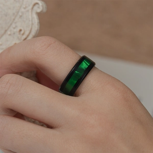 Detailed close-up of a men's black stainless steel ring featuring a vibrant green center band