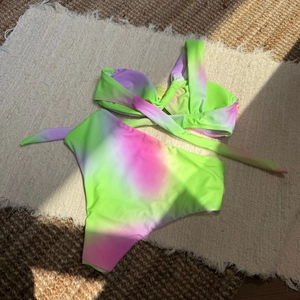 Bikini taille haute tie-dye avec haut croisé posé à plat sur un tapis texturé