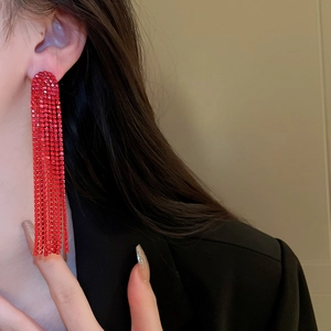 Close-up of red rhinestone long tassel earrings worn by a model in black suit