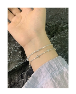 Macro shot of silver S925 beaded bracelet and twist chain on wrist with stone background