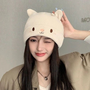 Detail of cream knitted hat featuring 3D cat ears and cute animal face embroidery