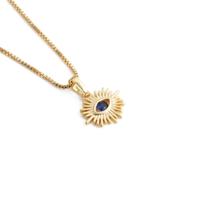 Detailed view of a golden evil eye pendant necklace featuring a central blue gemstone