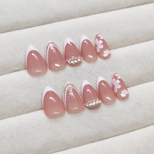 Almond shaped French press-on nails with pink base, white flowers and rhinestones