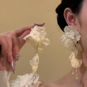 Detail showing elegant large white fabric flower drop earrings with pearls and long tassels