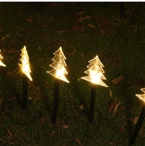 Detail of transparent Christmas tree ground stakes with warm LED lights on night lawn