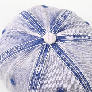 Close-up top view of a purple washed cotton baseball cap with white contrast stitching