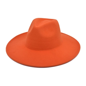Detailed view of a bright orange wide brim wool felt fedora hat with a classic creased crown