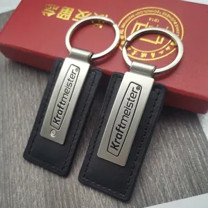 Pair of minimalist black PU leather and matte silver metal car keychains with stitching