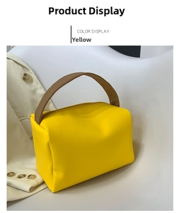 Close-up of a stylish orange square handbag with brown leather strap and zipper closure
