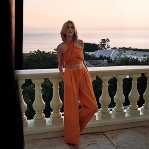 Damen-Set mit orangefarbenem Neckholder-Crop-Top und weiter Hose für den Sommerurlaub