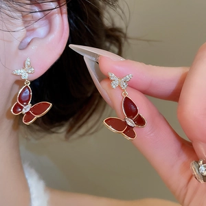 Macro shot of elegant burgundy enamel butterfly earrings with gold plating and zircon